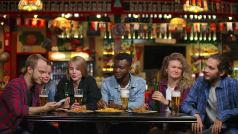 Eine-Große-Gruppe-Von-Freunden-Sitzt-In-Der-Bar-Am-Tisch,-Lacht,-Plaudert-Und-Trinkt-Bier.